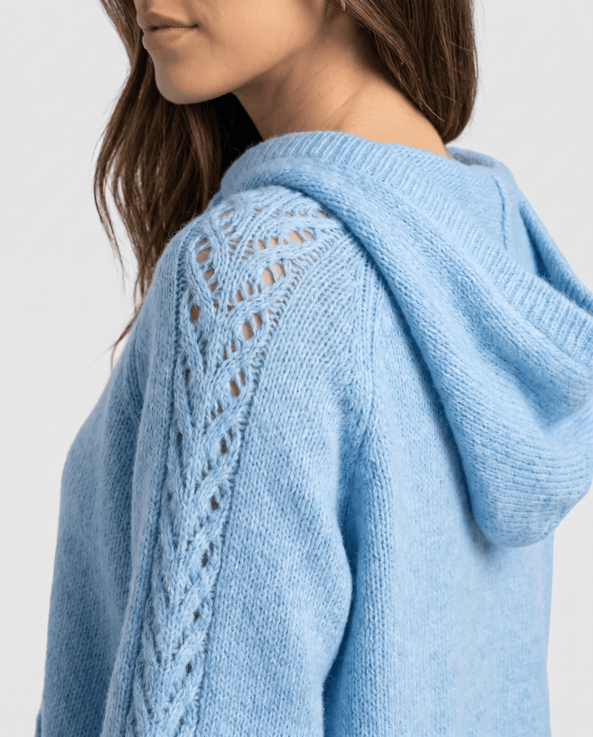 Side close-up of the light blue hood and open-stitch detail along the sleeve