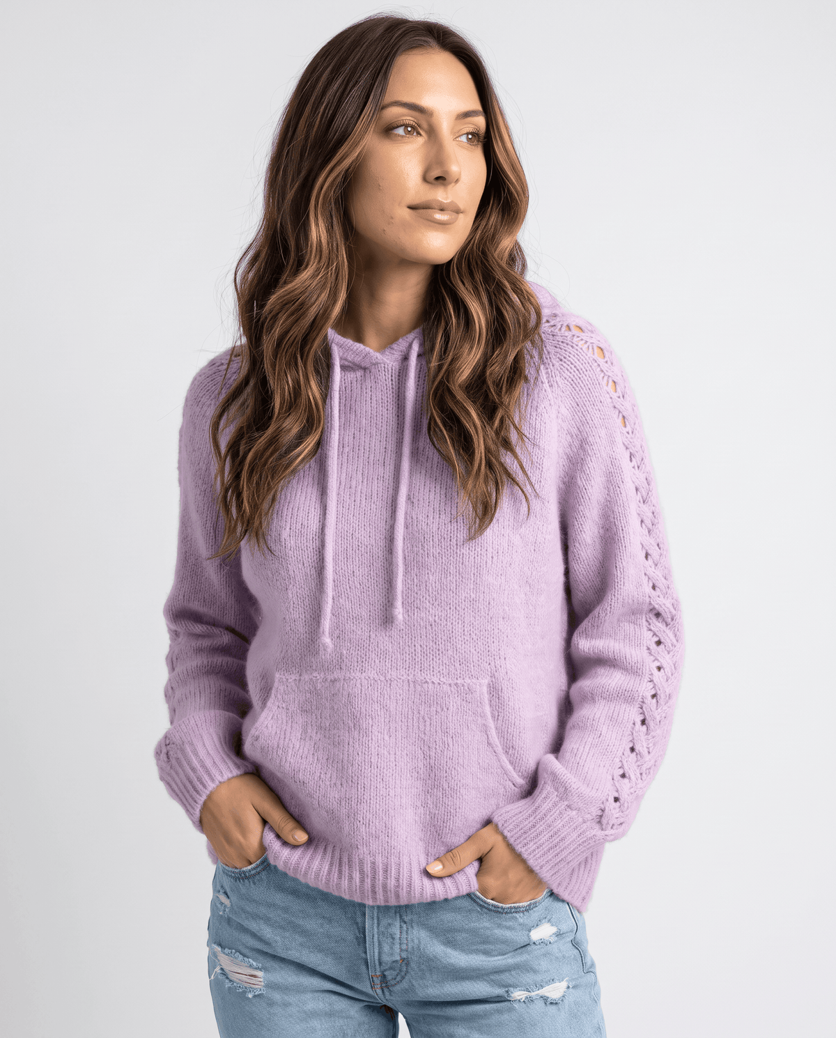 Purple hooded sweater with open-stitch sleeves and hands in the jeans pockets, front view