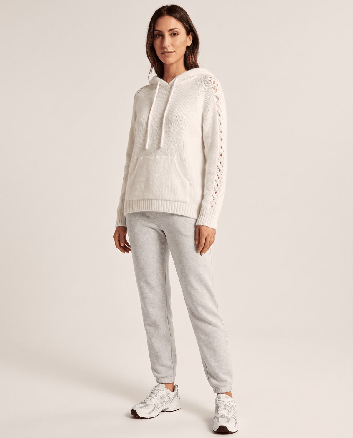 Full-length look pairing the white hooded sweater with light gray joggers and sneakers