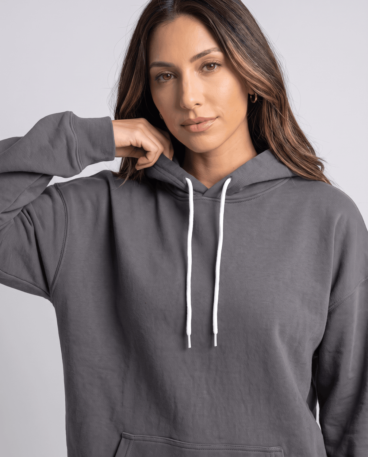 Close-up of the gray hoodie with white drawstrings and a hand at the shoulder