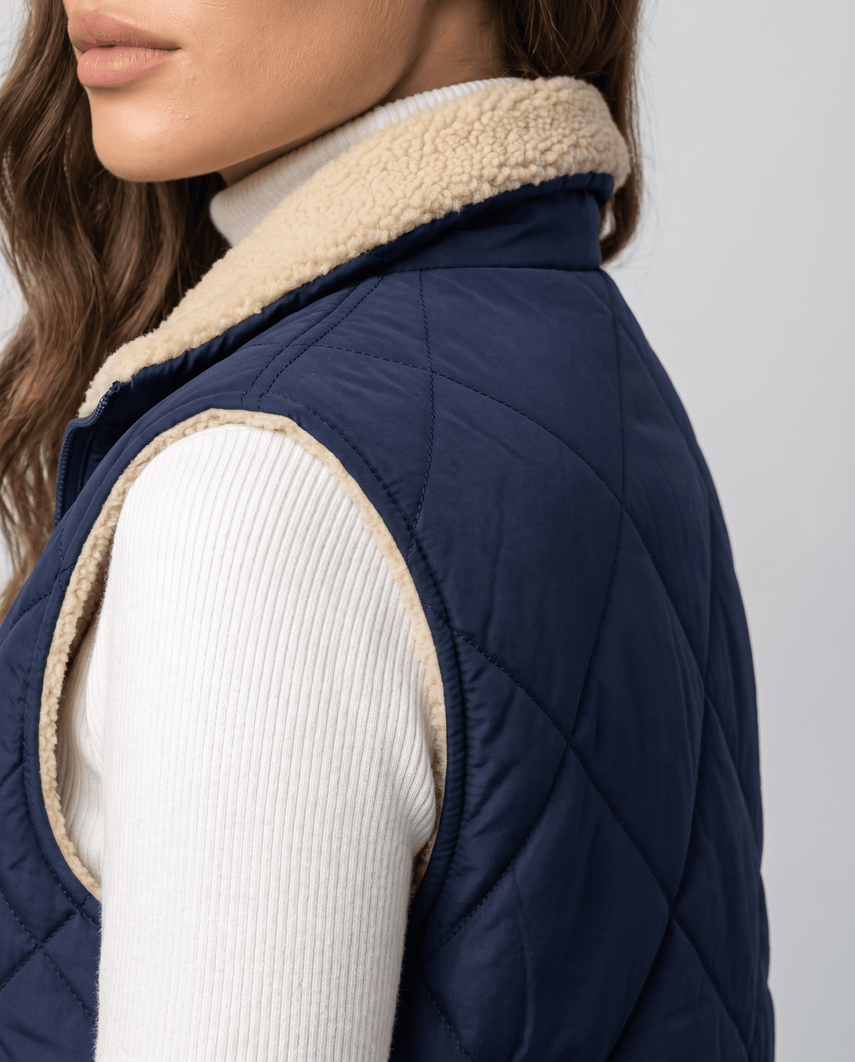 Side view of blue diamond-quilted vest stand collar and shoulder
