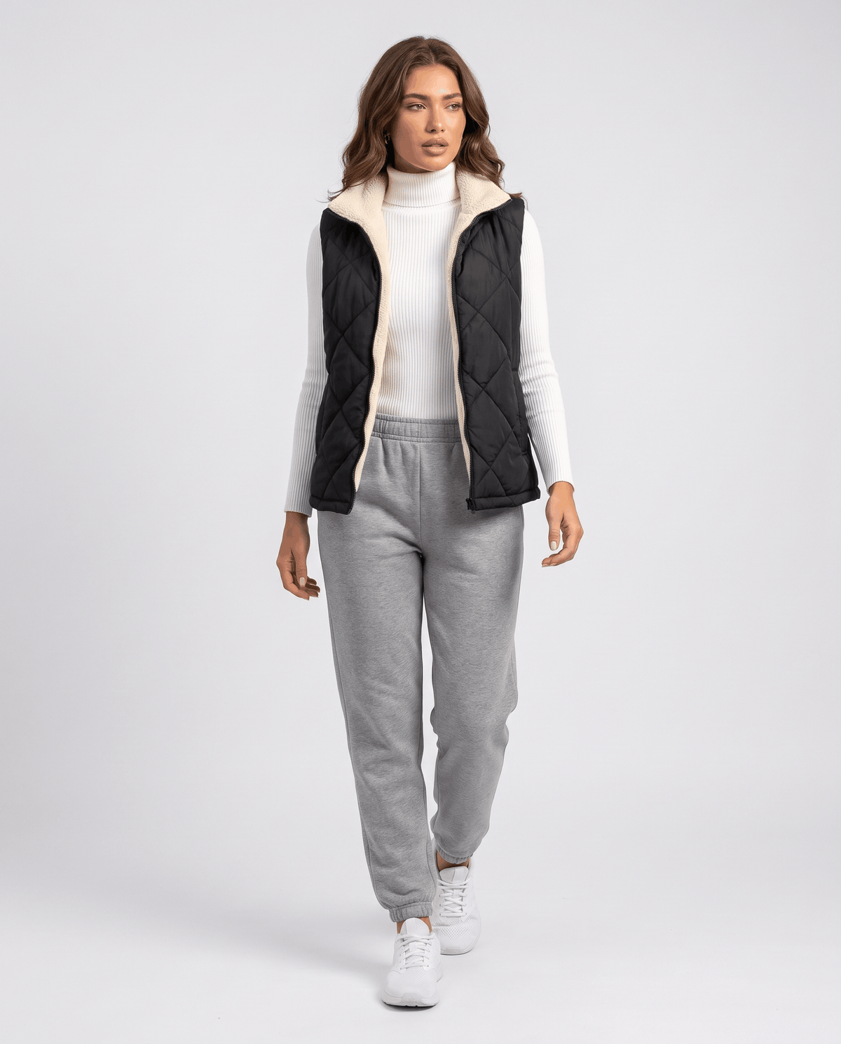 Full-length look with dark quilted vest, gray joggers and sneakers while walking