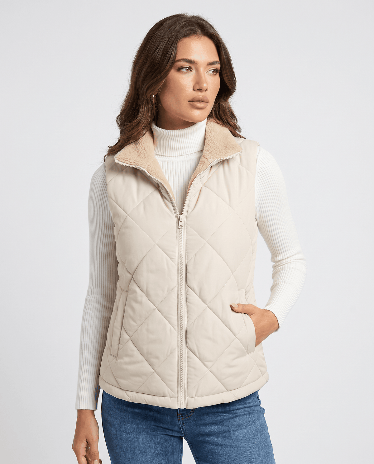 Light beige quilted vest with one hand in the zip pocket, front view