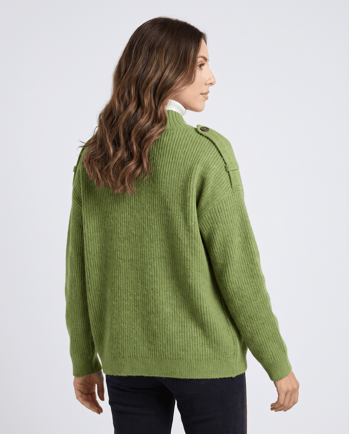 Back view of woman in green ribbed knit cardigan with relaxed fit over a white turtleneck