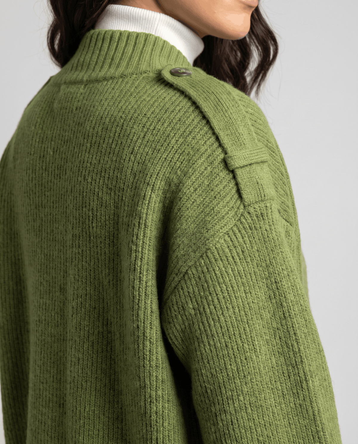 Close-up of green ribbed knit cardigan shoulder strap button and stand collar detail
