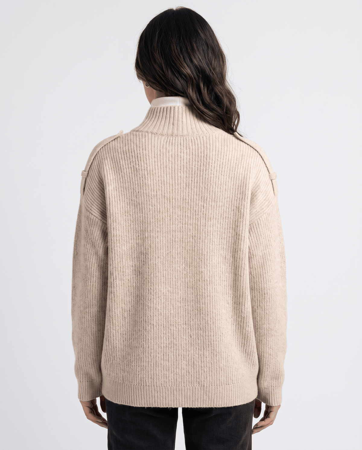 Back view of woman in light beige ribbed knit cardigan over a white turtleneck