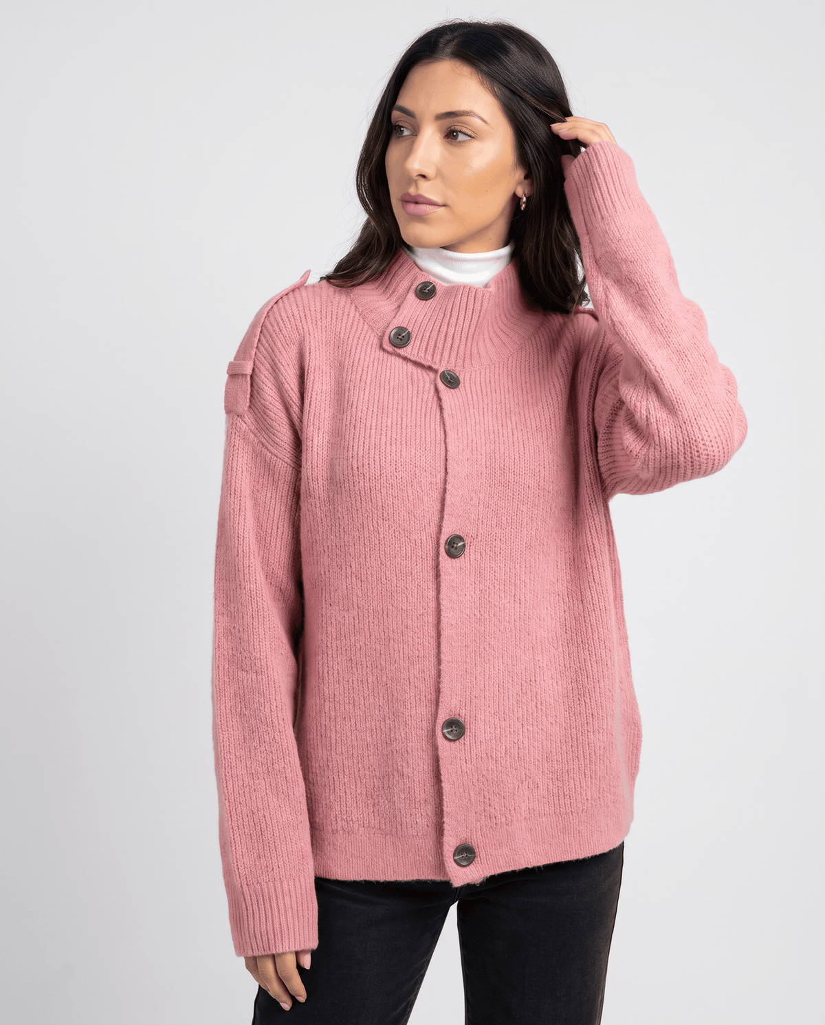 Woman wearing pink ribbed knit cardigan with stand collar and off-center button front