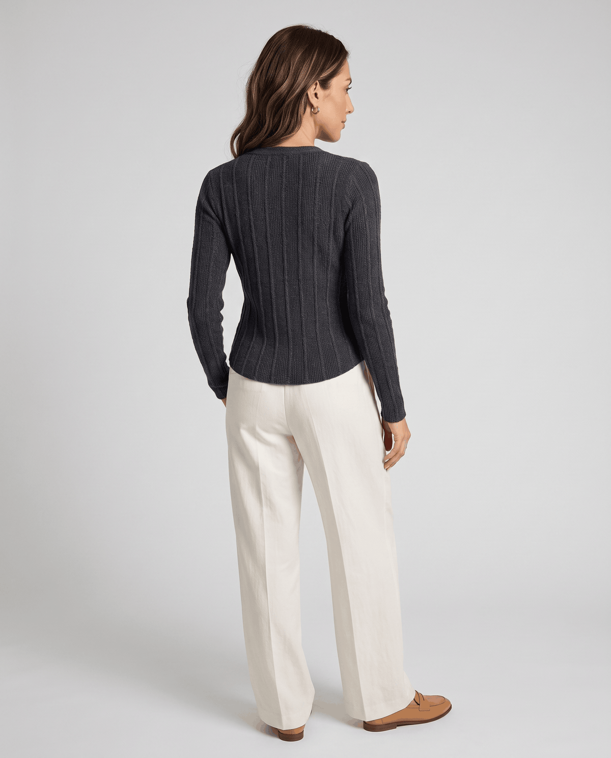 Back view of dark gray ribbed cardigan worn with cream wide-leg trousers