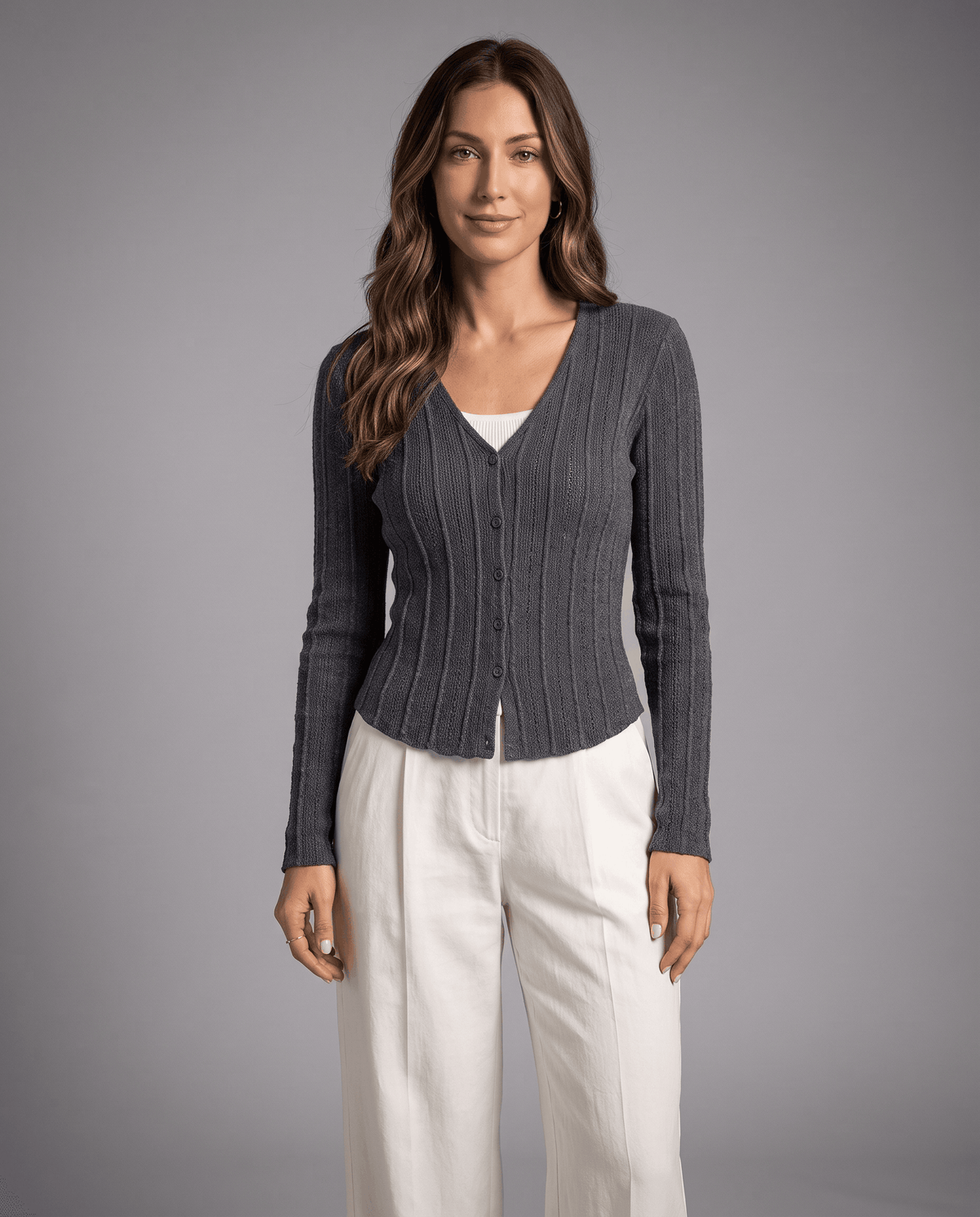 Dark gray ribbed button-front cardigan styled with cream trousers against a studio backdrop