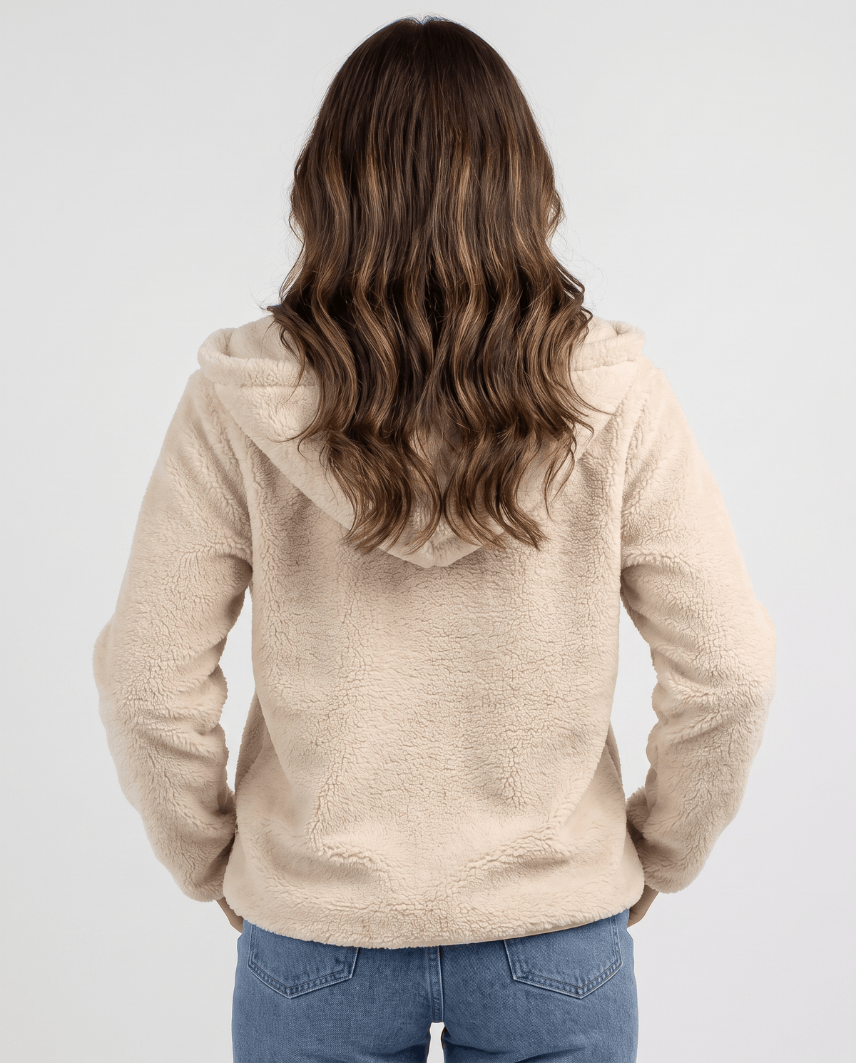Back of cream sherpa hoodie with long hair over the hood and jeans