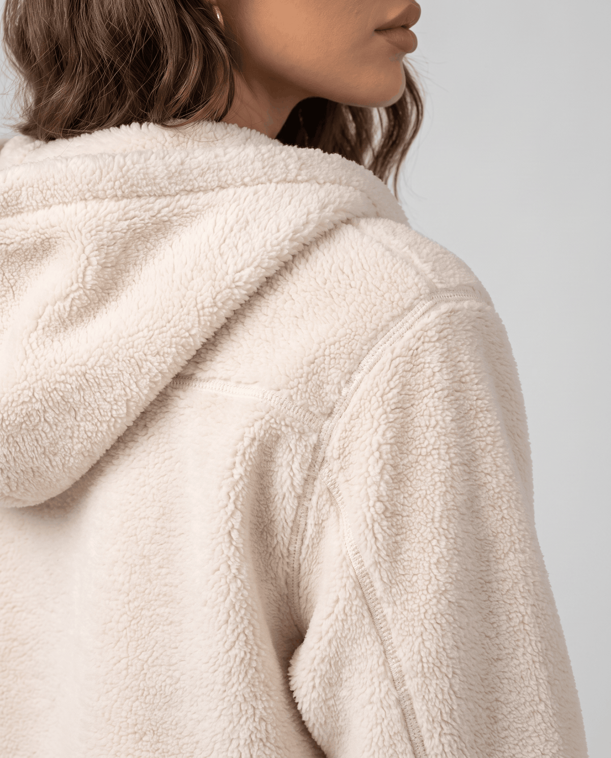 Side close-up of cream sherpa hood and shoulder with soft fuzzy texture