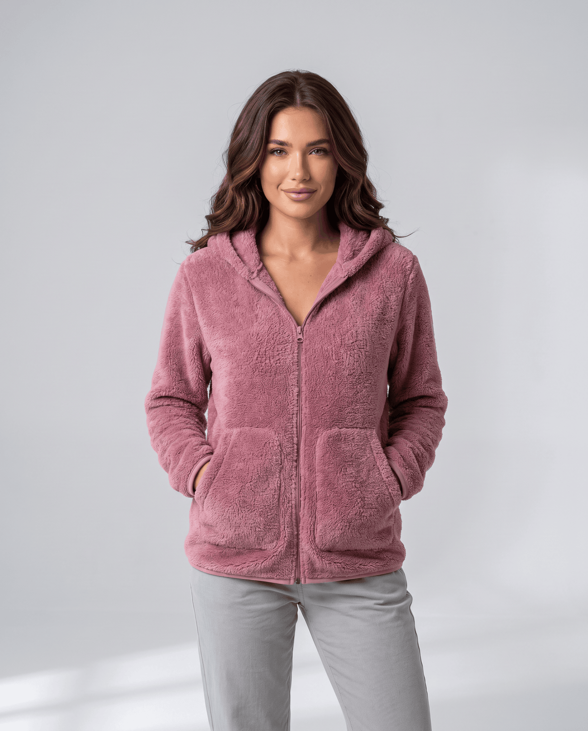 Front view of dusty pink sherpa hoodie zipped up with hands in the pockets