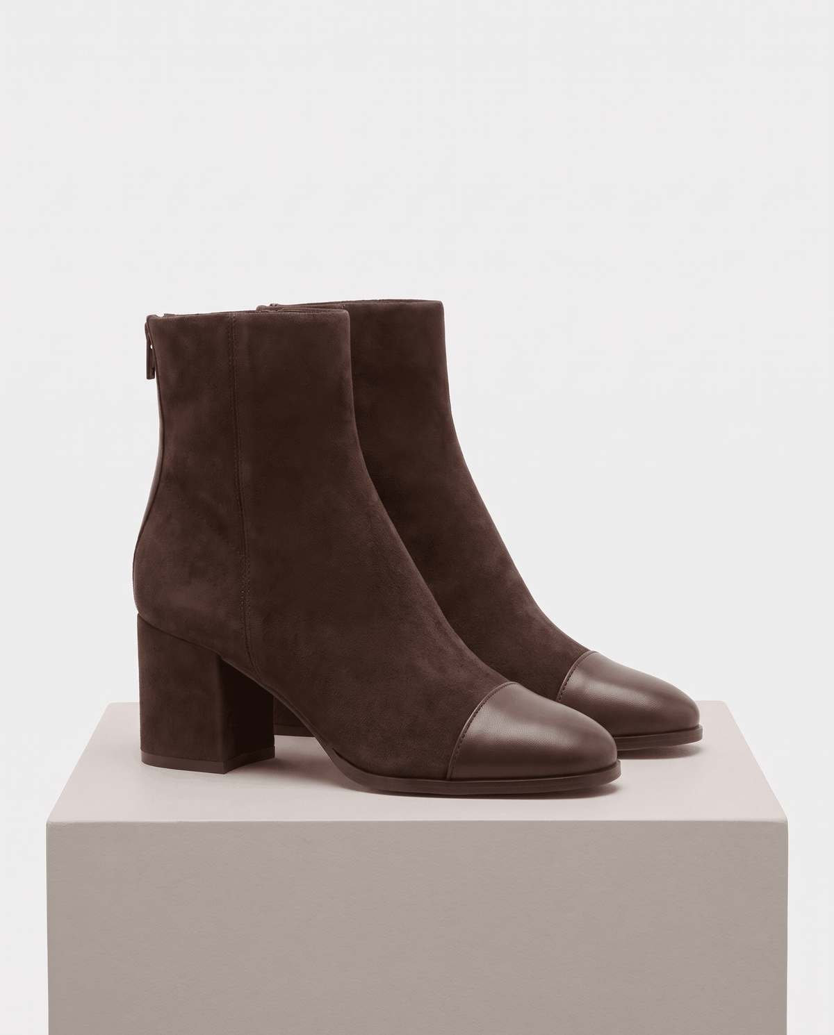 Pair of brown suede ankle boots displayed on a pedestal