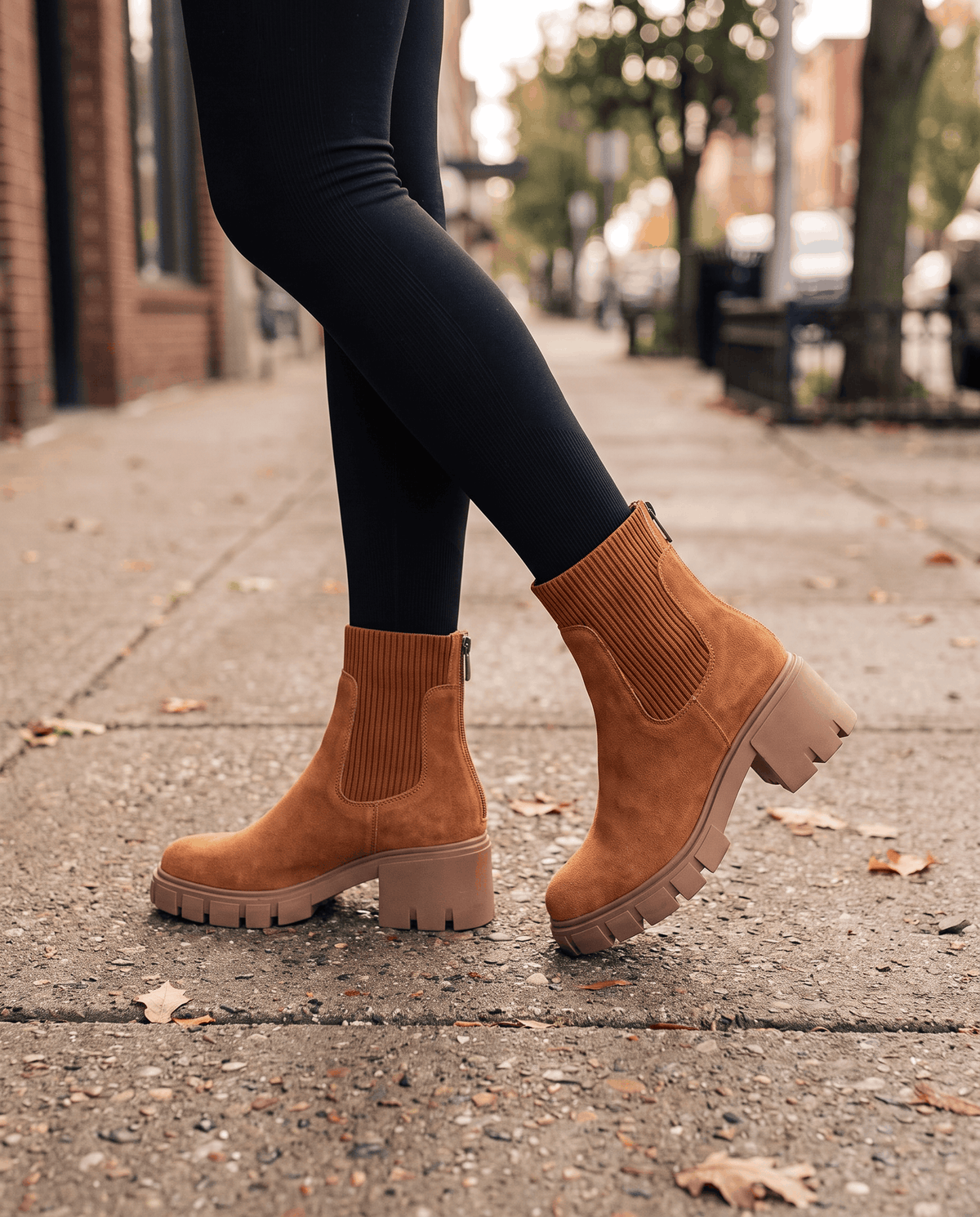 Brown suede platform boots worn with dark leggings on pavement