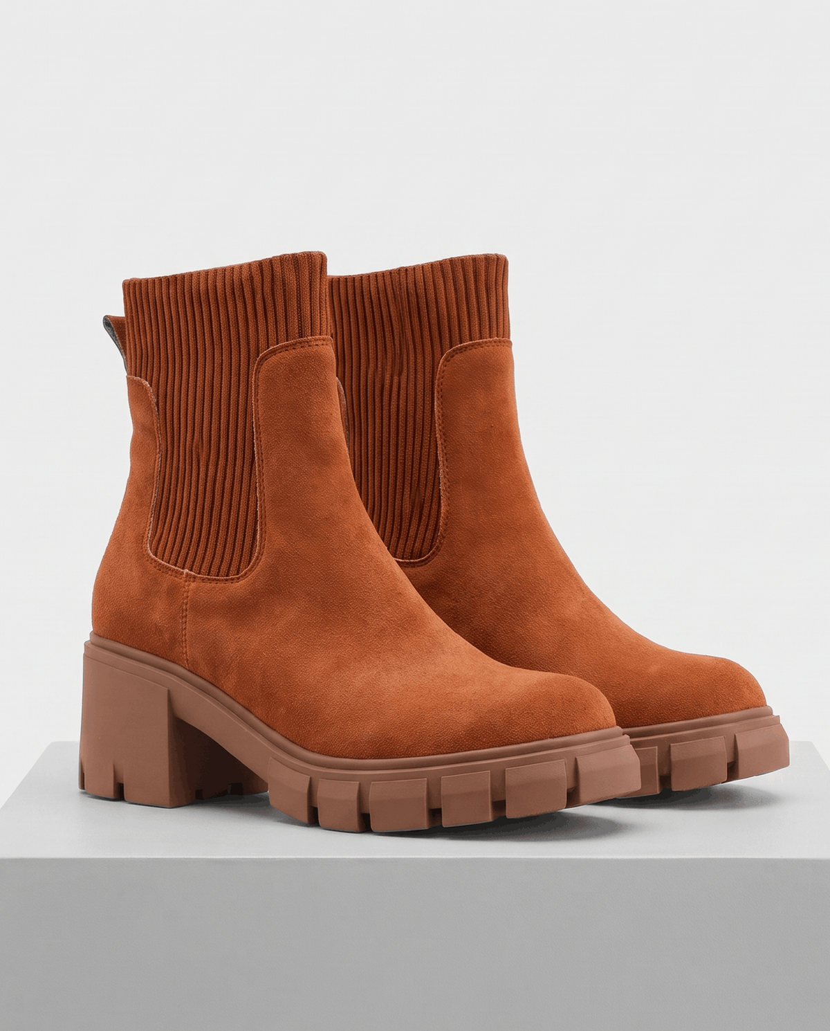 Pair of brown suede platform boots on a white pedestal