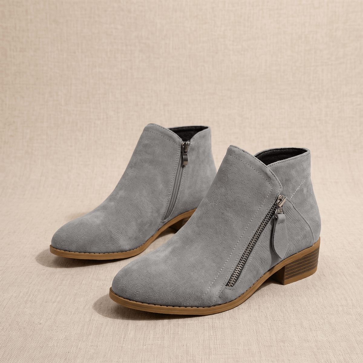 Pair of gray suede ankle boots with side zippers on a neutral background.