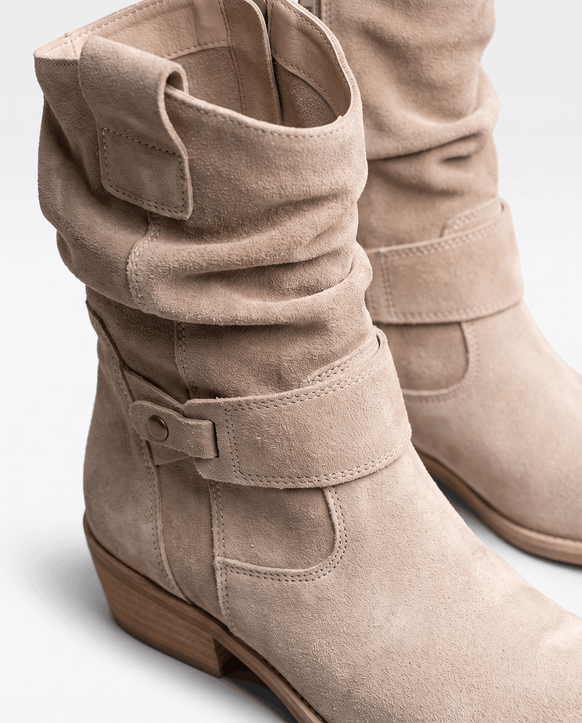 Close-up of beige suede with soft slouch folds and a strap
