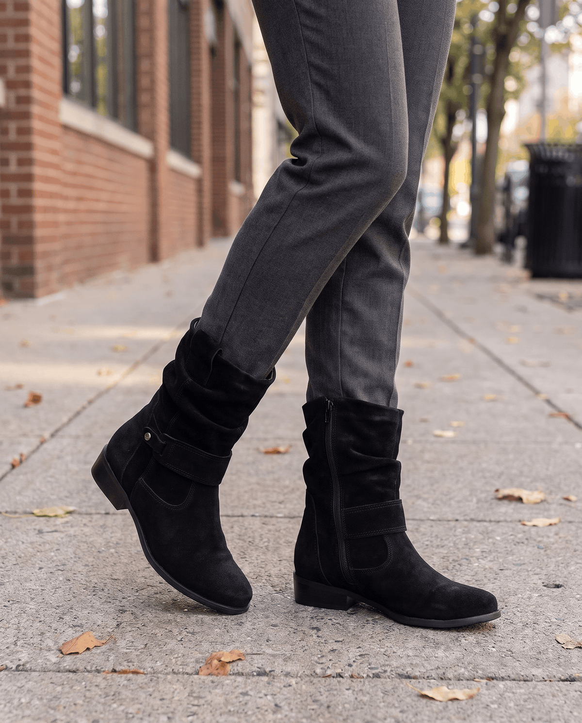 Black suede slouch boots worn with grey trousers on a street