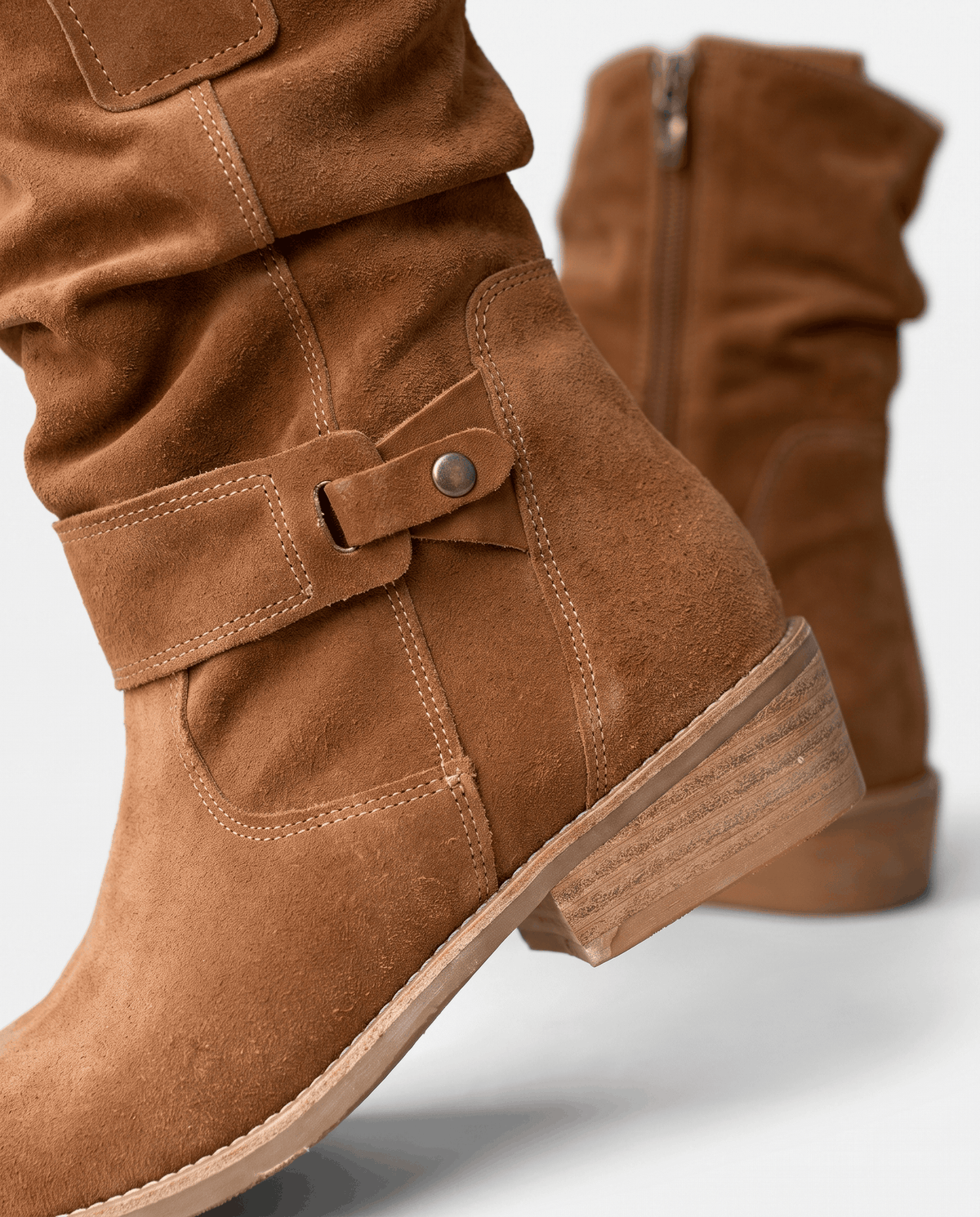 Tan suede boot with tab strap, rivet snap and stacked heel