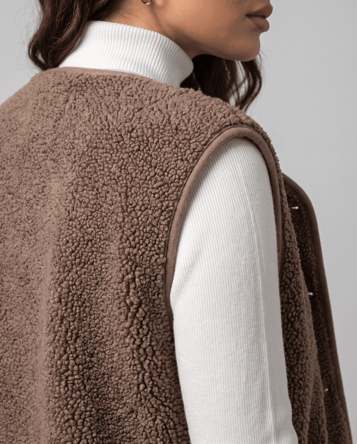 Side close-up of taupe teddy fleece vest showing the curly texture and armhole