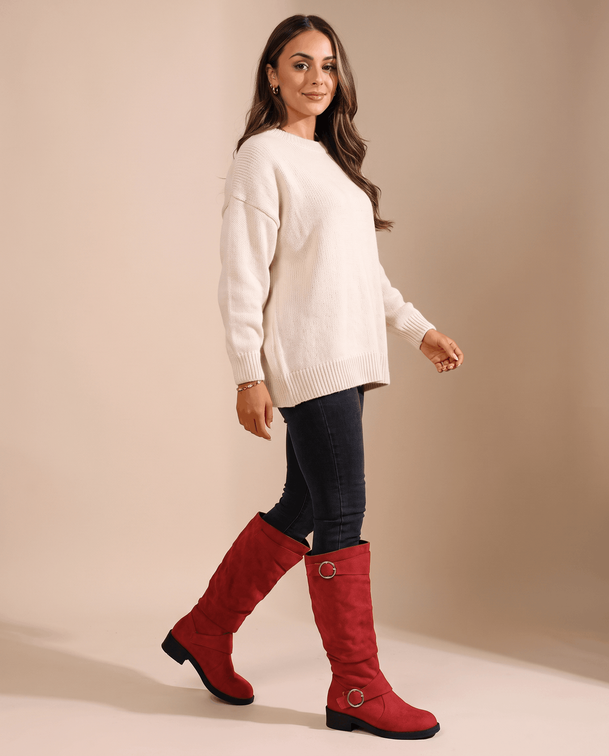 Red vegan suede knee-high boots with a slouched shaft, twin ring straps, and a low stacked heel worn with dark jeans.
