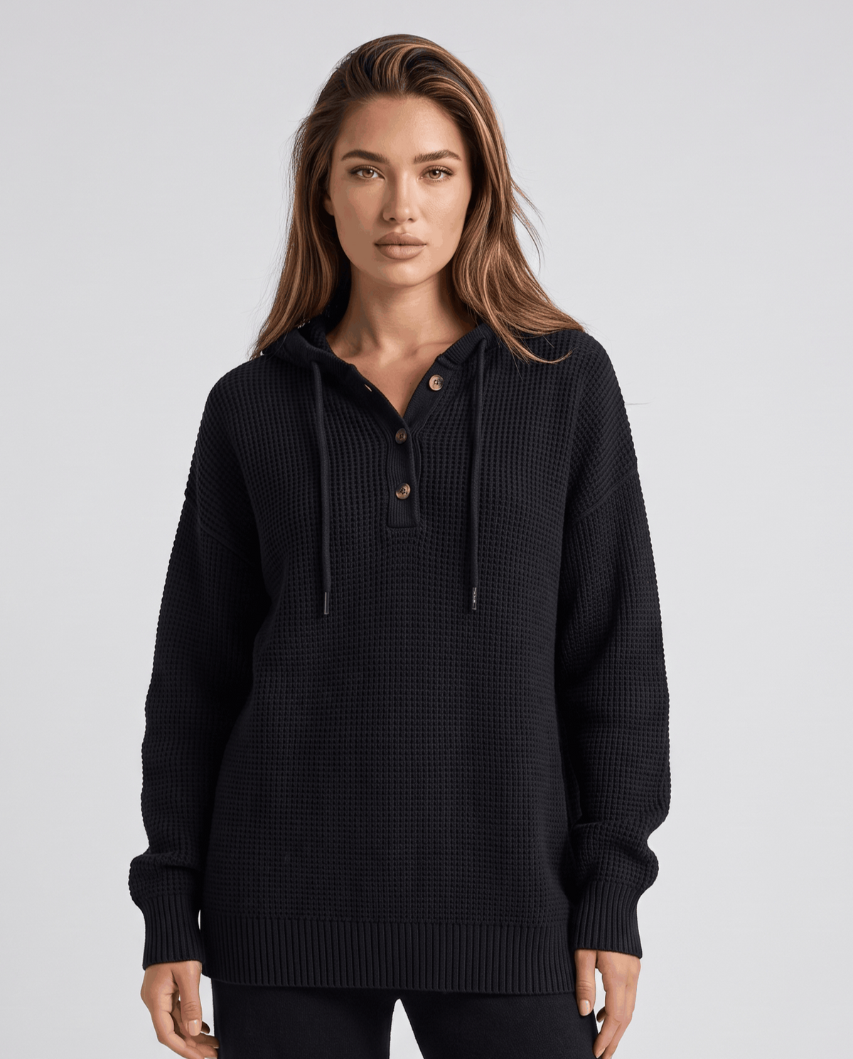 Black waffle knit hoodie with drawstrings and buttoned neckline, front view
