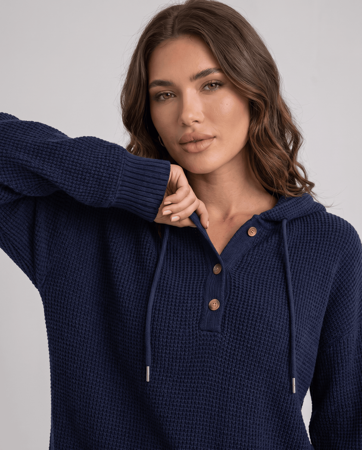 Close-up of the navy hoodie buttoned neckline and drawstrings with a hand at the shoulder