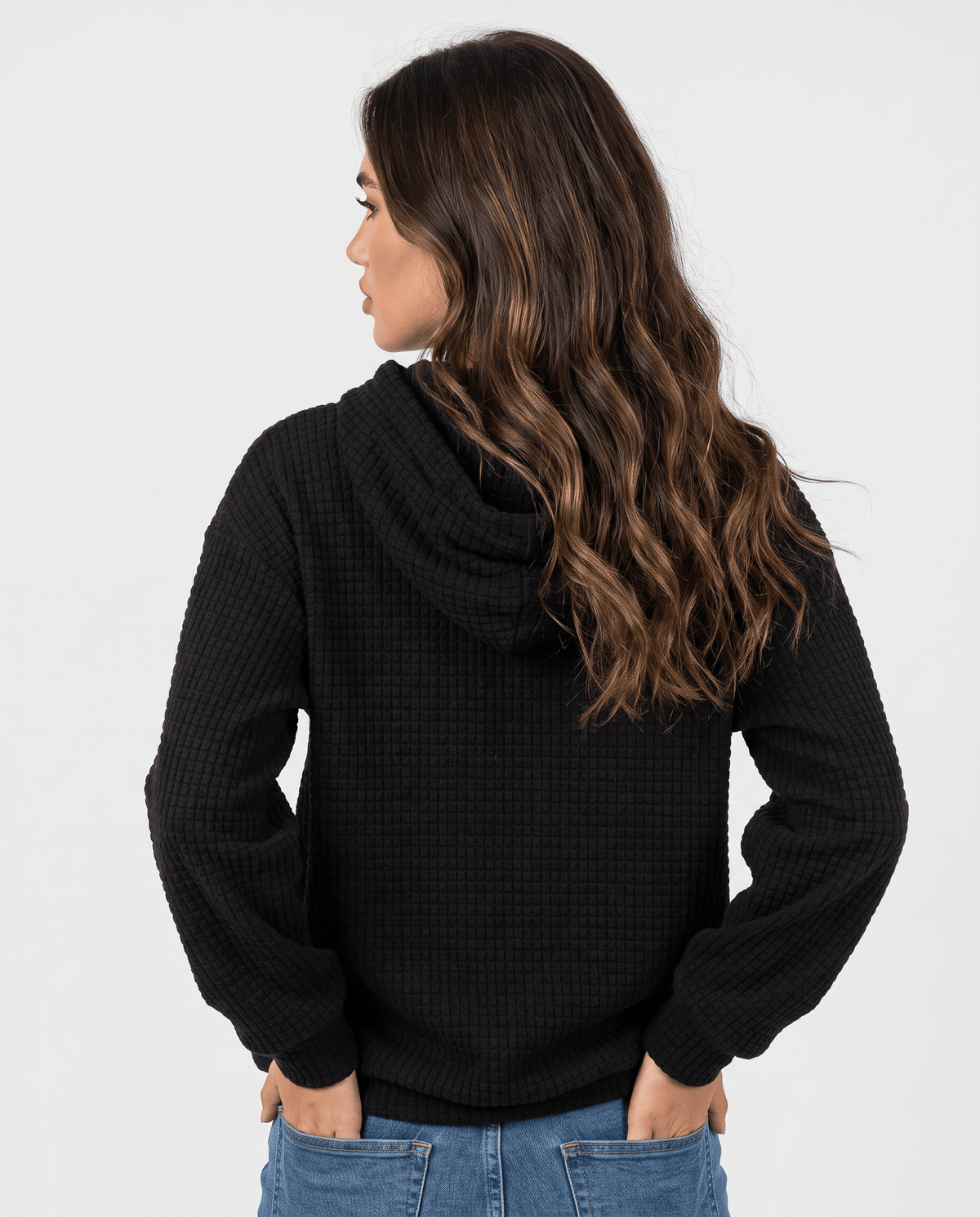 Back of black pullover hoodie showing the hood and relaxed waffle knit body