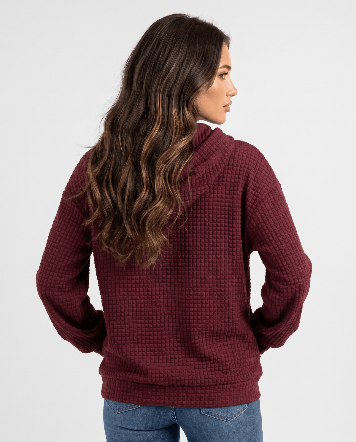Back of burgundy pullover hoodie with long wavy hair over the hood