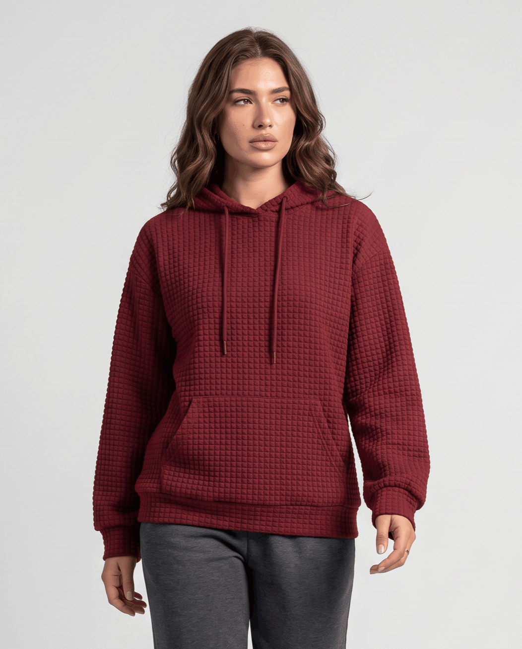 Front view of burgundy waffle knit hoodie worn with dark pants and drawstrings