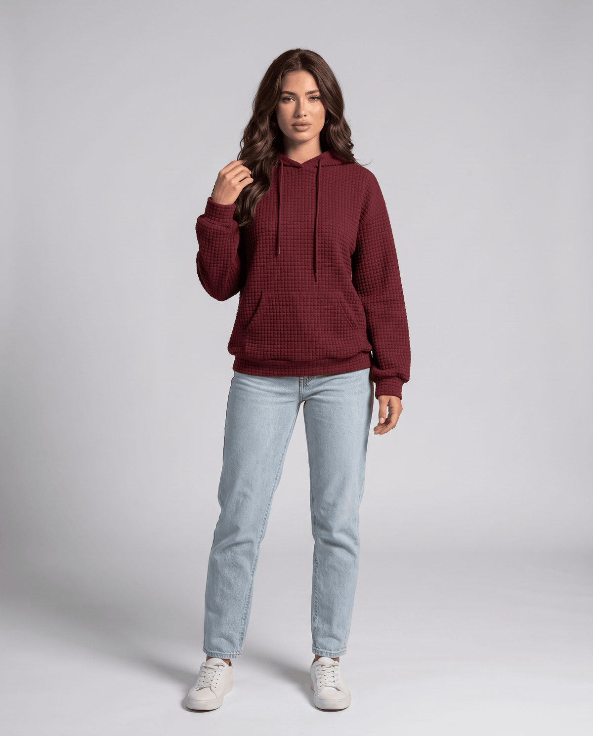 Full-length burgundy hoodie styled with light blue jeans and white sneakers
