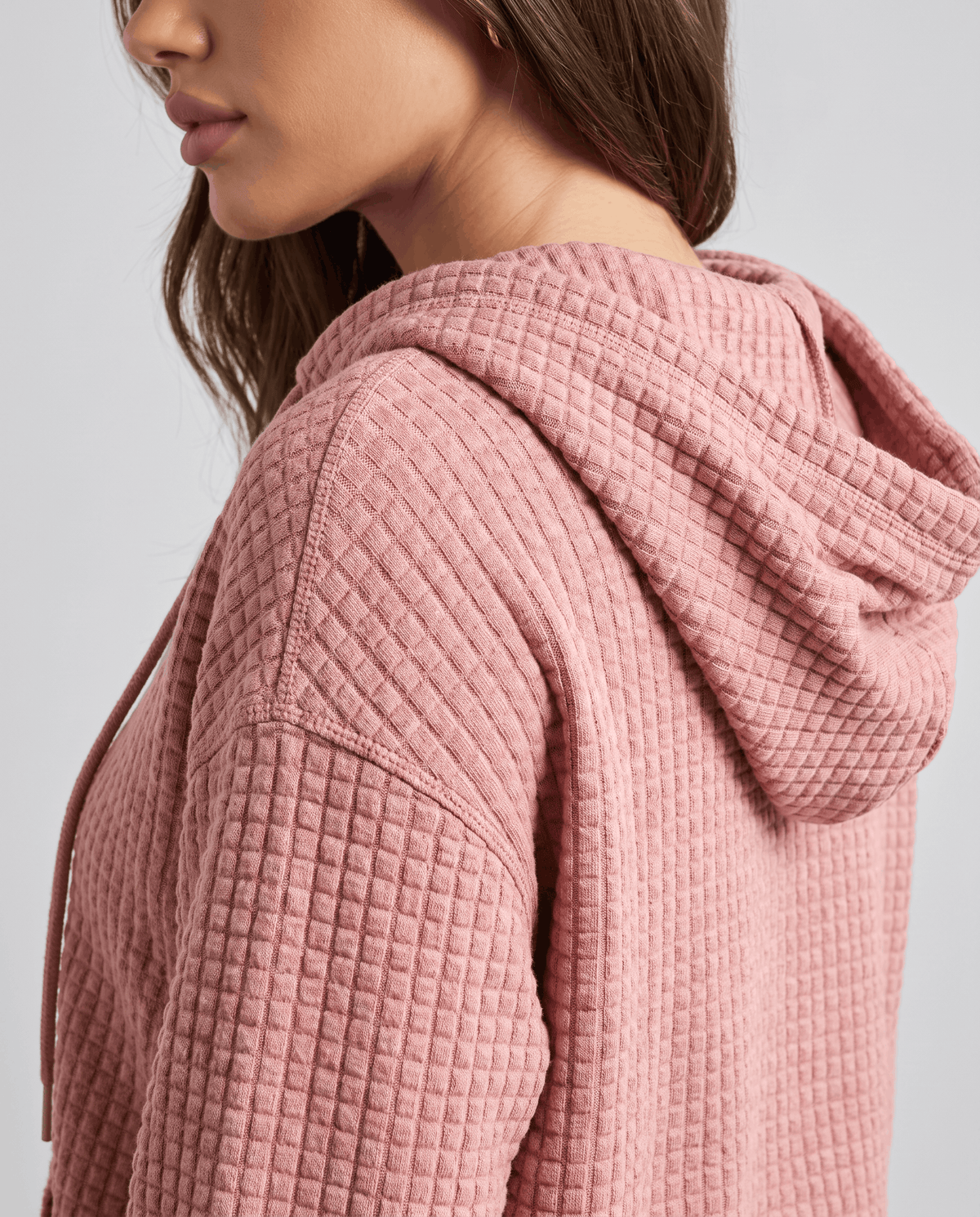 Side view of dusty pink hoodie showing the raised waffle texture and soft hood