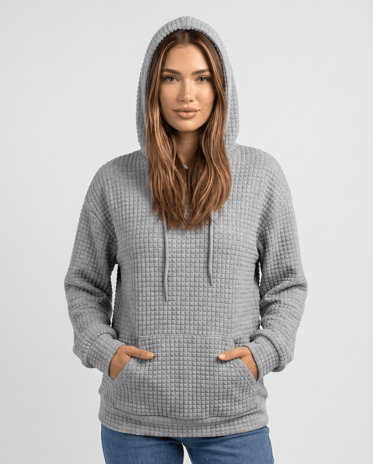 Front view of gray waffle knit hoodie with hood up and hands in kangaroo pocket