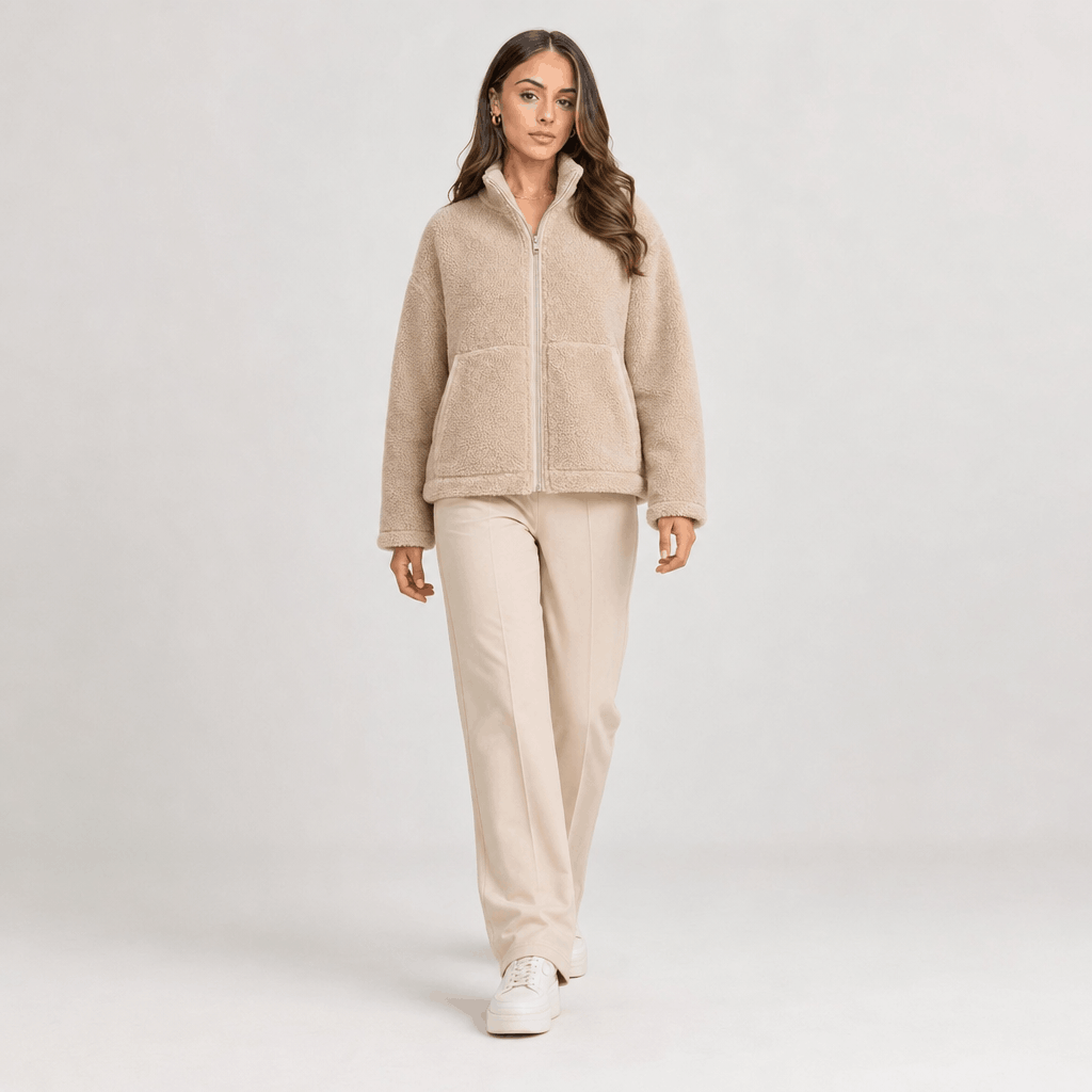 Full-body view of a female model wearing the light beige sherpa jacket with matching light-colored trousers.