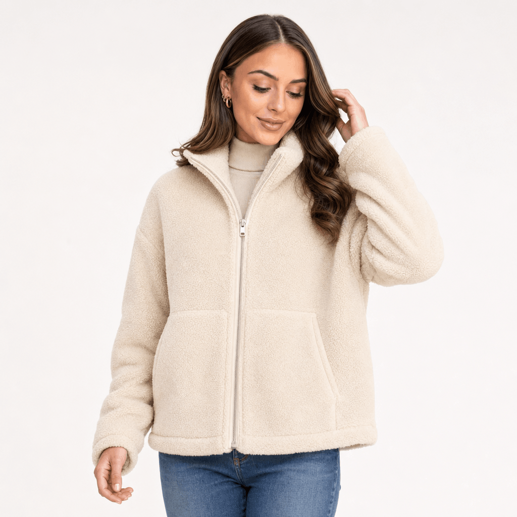 Female model wearing the light beige sherpa zip-up jacket with blue jeans in a relaxed pose.