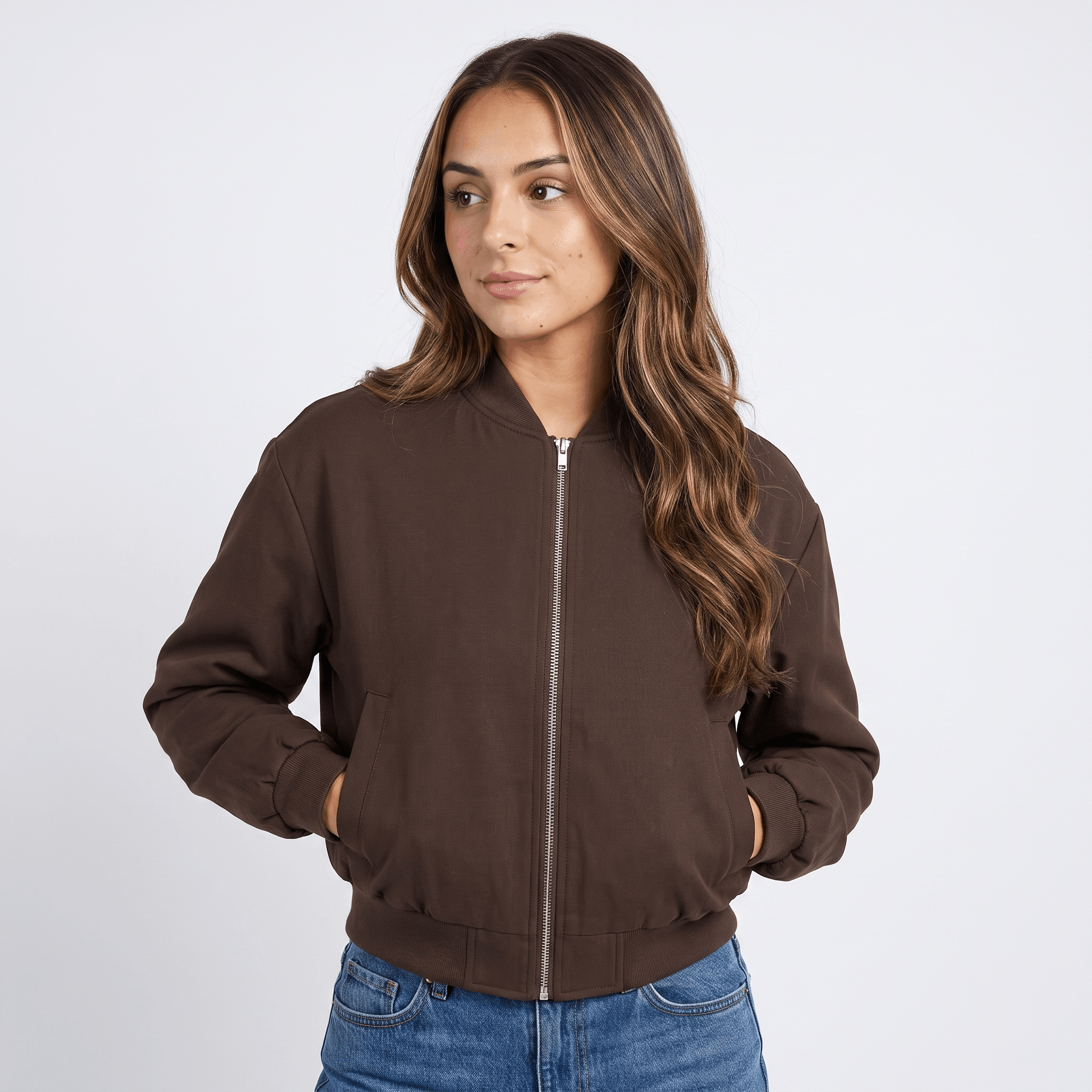 Female model wearing a dark brown zip-up bomber jacket with a stand collar, ribbed cuffs and hem, and side pockets, paired with blue jeans.