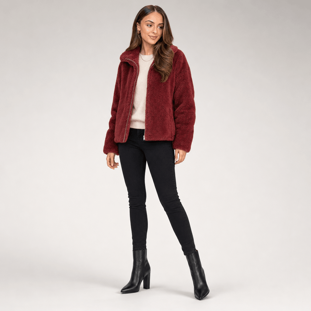 Full-body view of a female model wearing the deep red sherpa fleece jacket with black trousers and ankle boots.