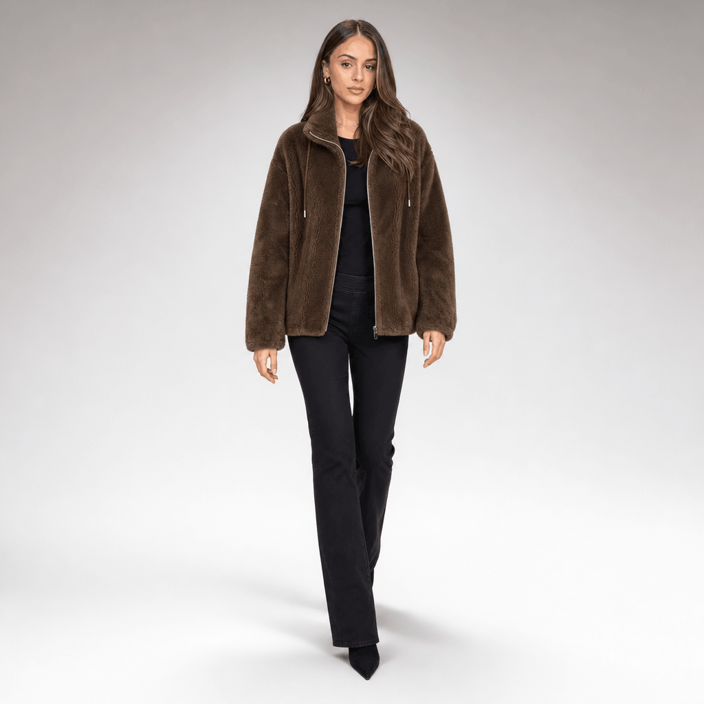 Full-body view of a female model wearing the brown sherpa fleece jacket with black trousers.