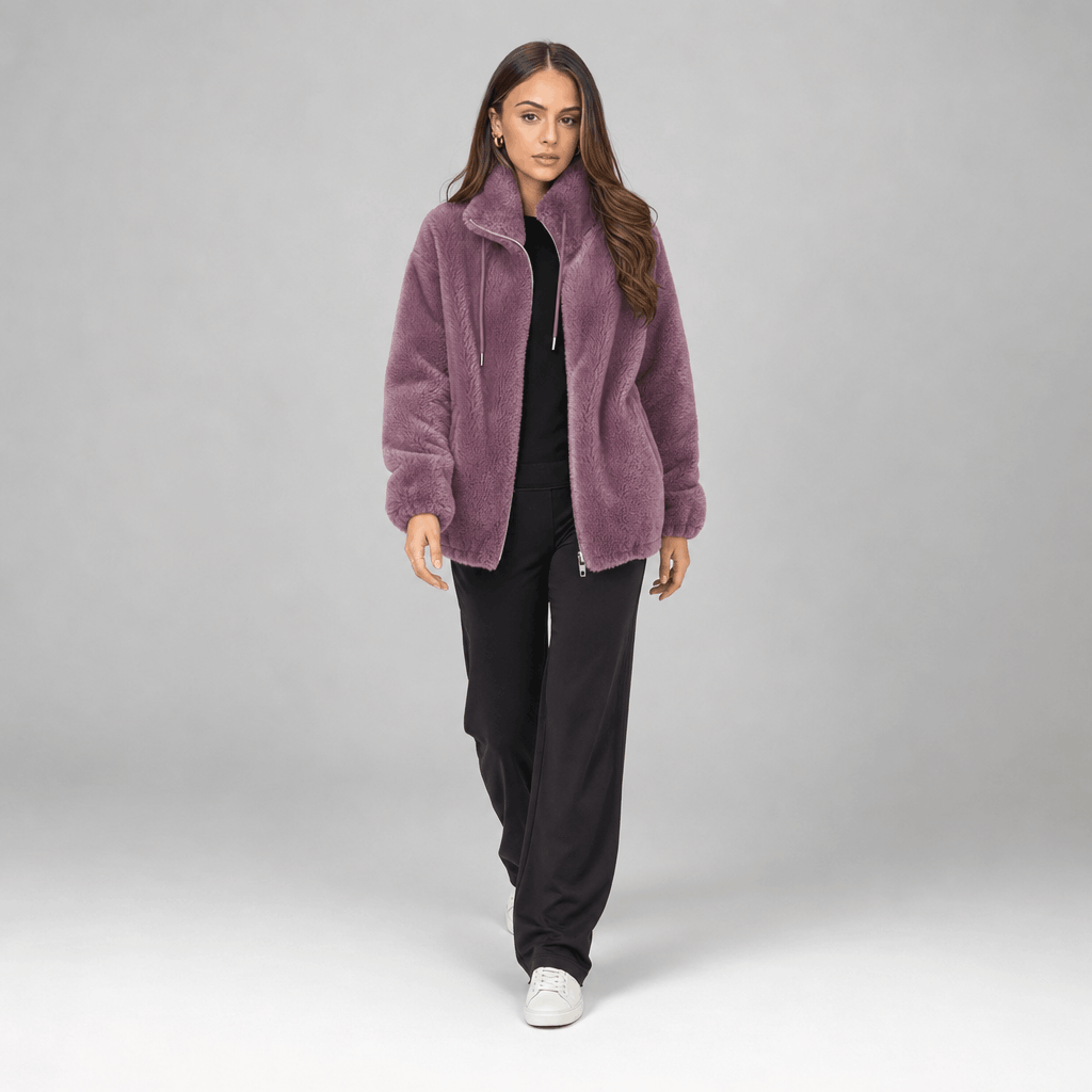 Full-body view of a female model wearing the dusty purple sherpa fleece jacket with black trousers.