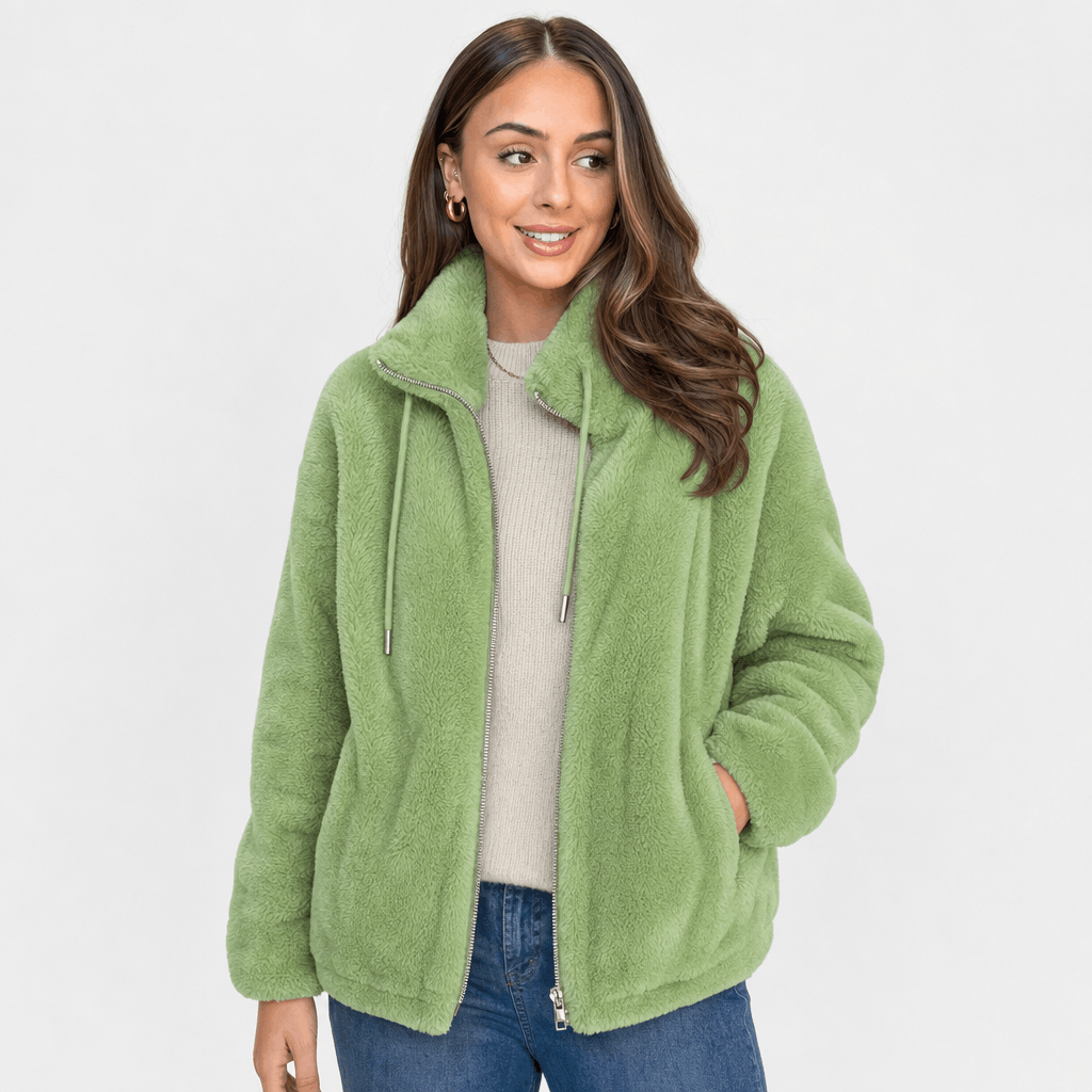 Female model wearing a light green sherpa fleece zip-up jacket with blue jeans.
