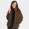 Female model wearing a brown sherpa fleece zip-up jacket with a high collar, paired with a black top and black trousers.