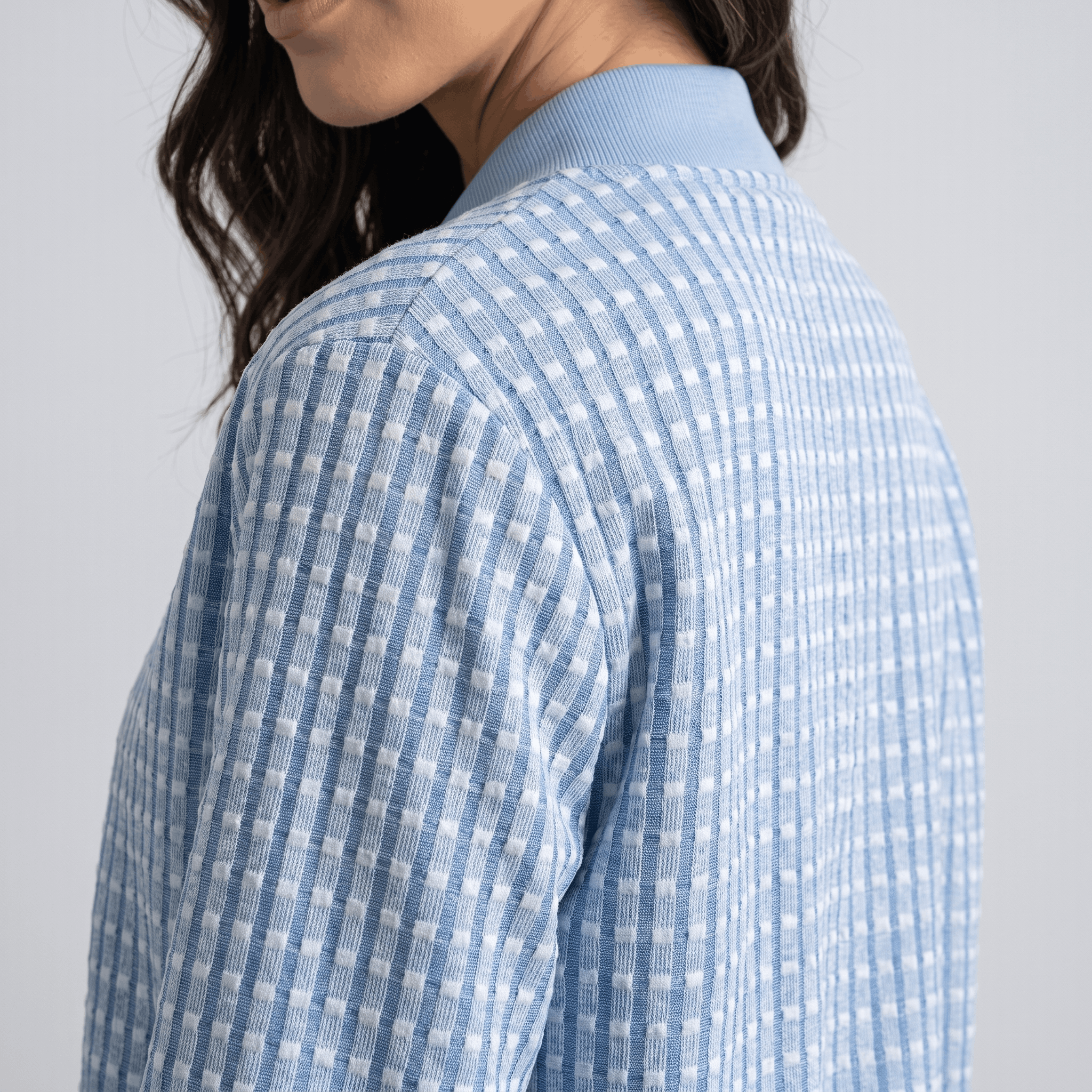 Close-up back and side view of the light blue jacket, showing the textured fabric and shoulder seams.