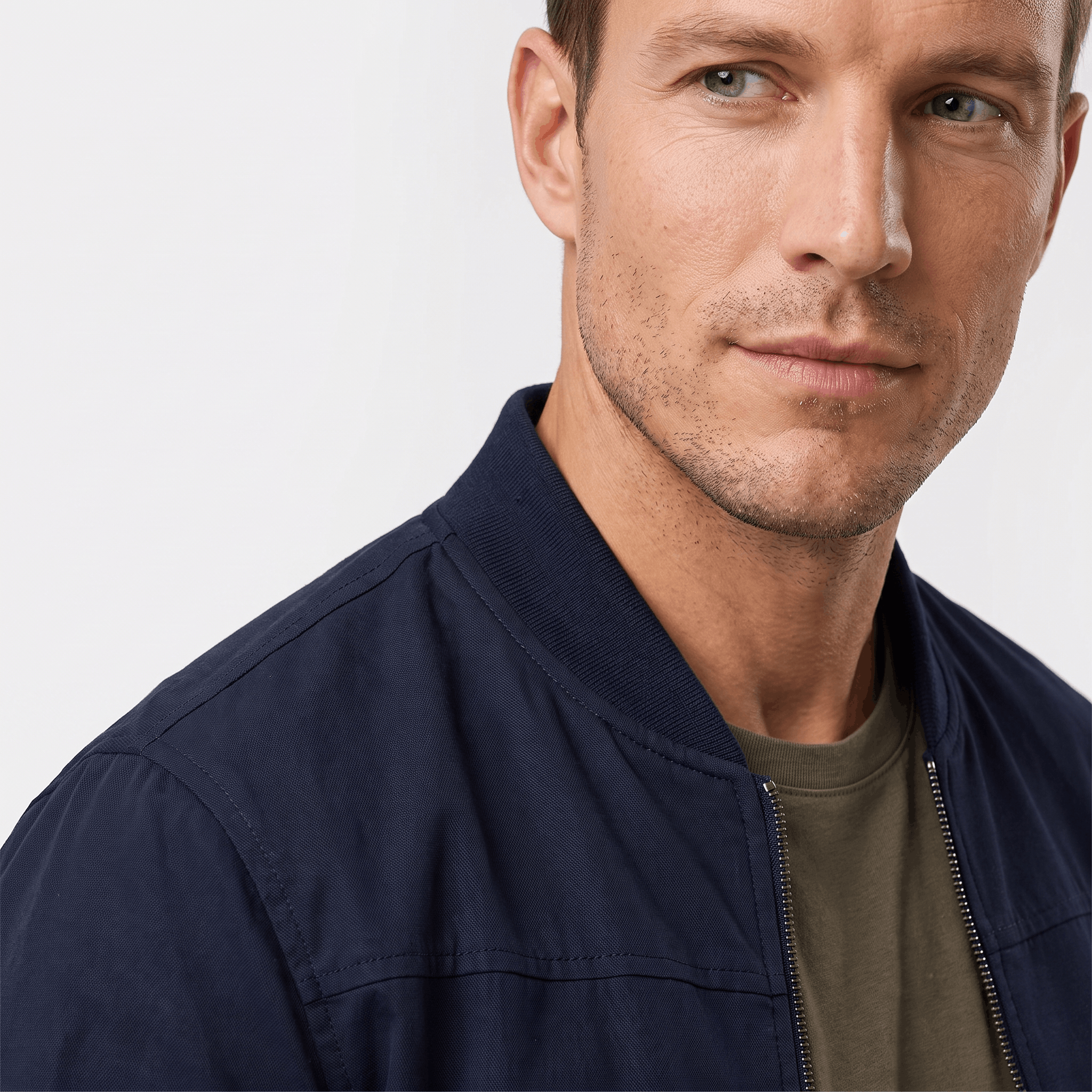 Male model wearing a navy blue bomber jacket over an olive green shirt, highlighting the collar and front zipper.