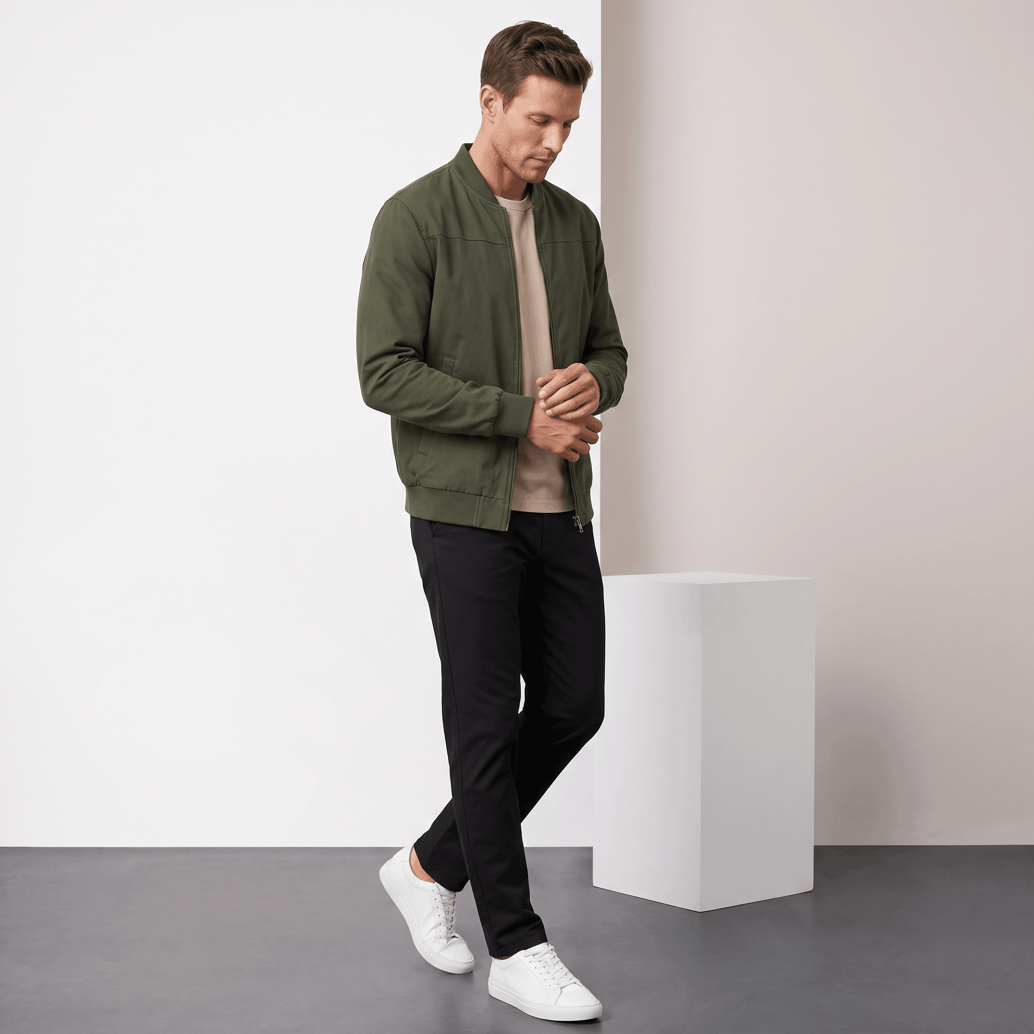Male model wearing the olive green bomber jacket with dark trousers and white sneakers.