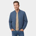 Male model wearing a blue bomber jacket over a beige shirt with blue jeans.