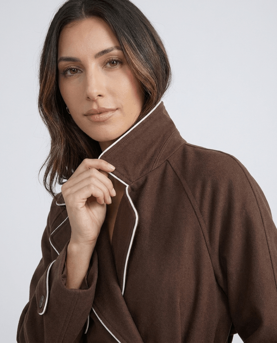 Brown belted trench coat for women worn by a female model, close-up showing contrast stitching and lapel collar