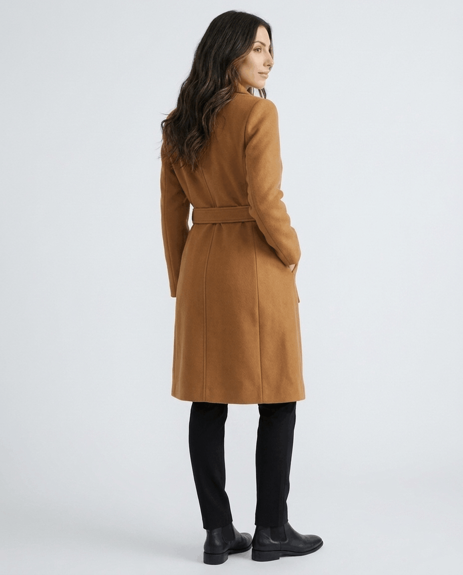 A woman wearing a brown belted wool trench coat, shown from the back with a tailored fit and long sleeves