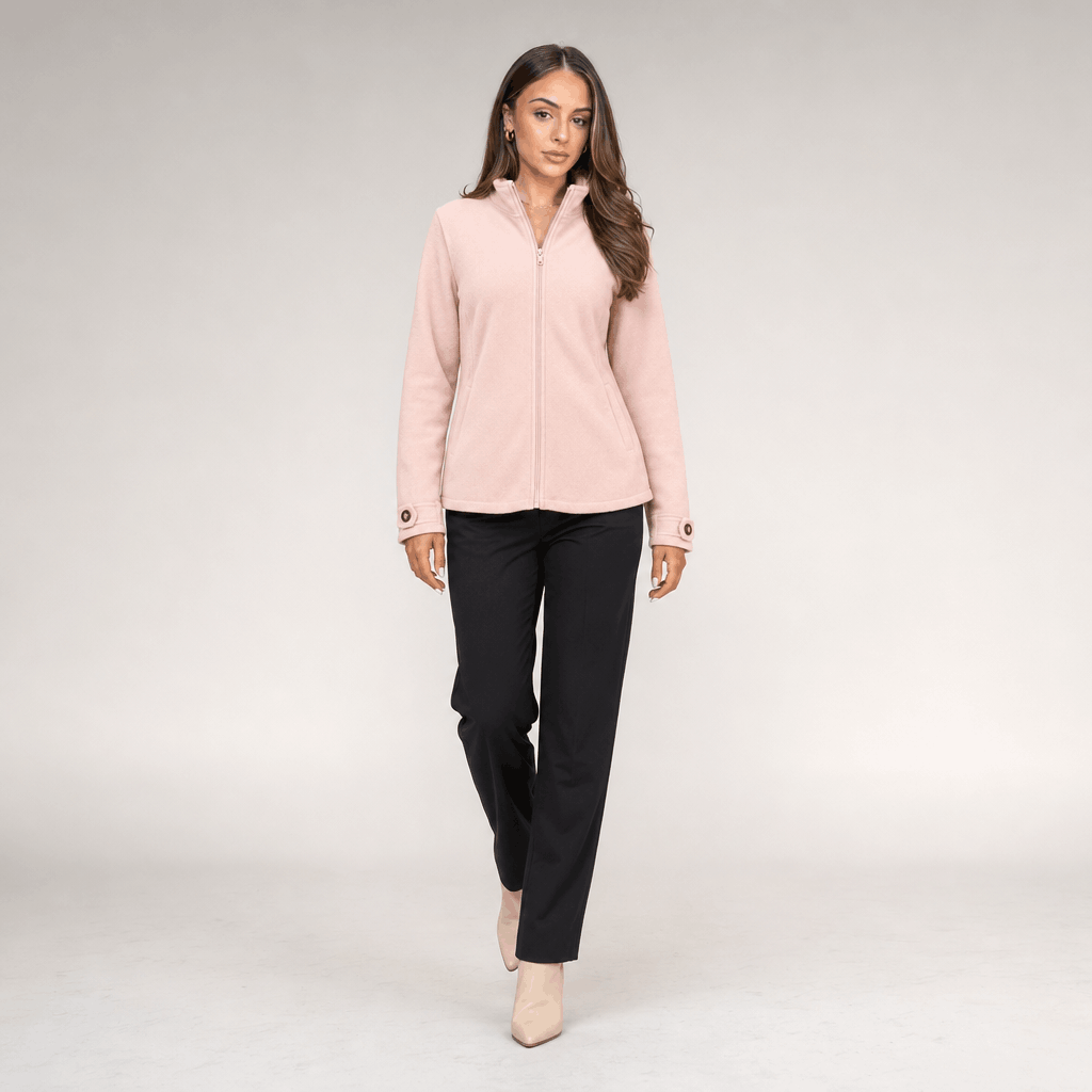Full-body view of a female model wearing a light blush pink zip-up jacket with black trousers.