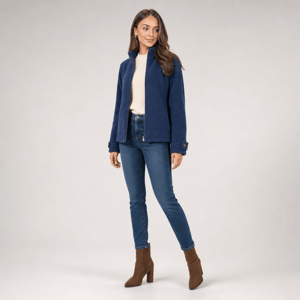 Full-body view of a female model wearing the navy blue jacket with blue jeans and brown ankle boots.