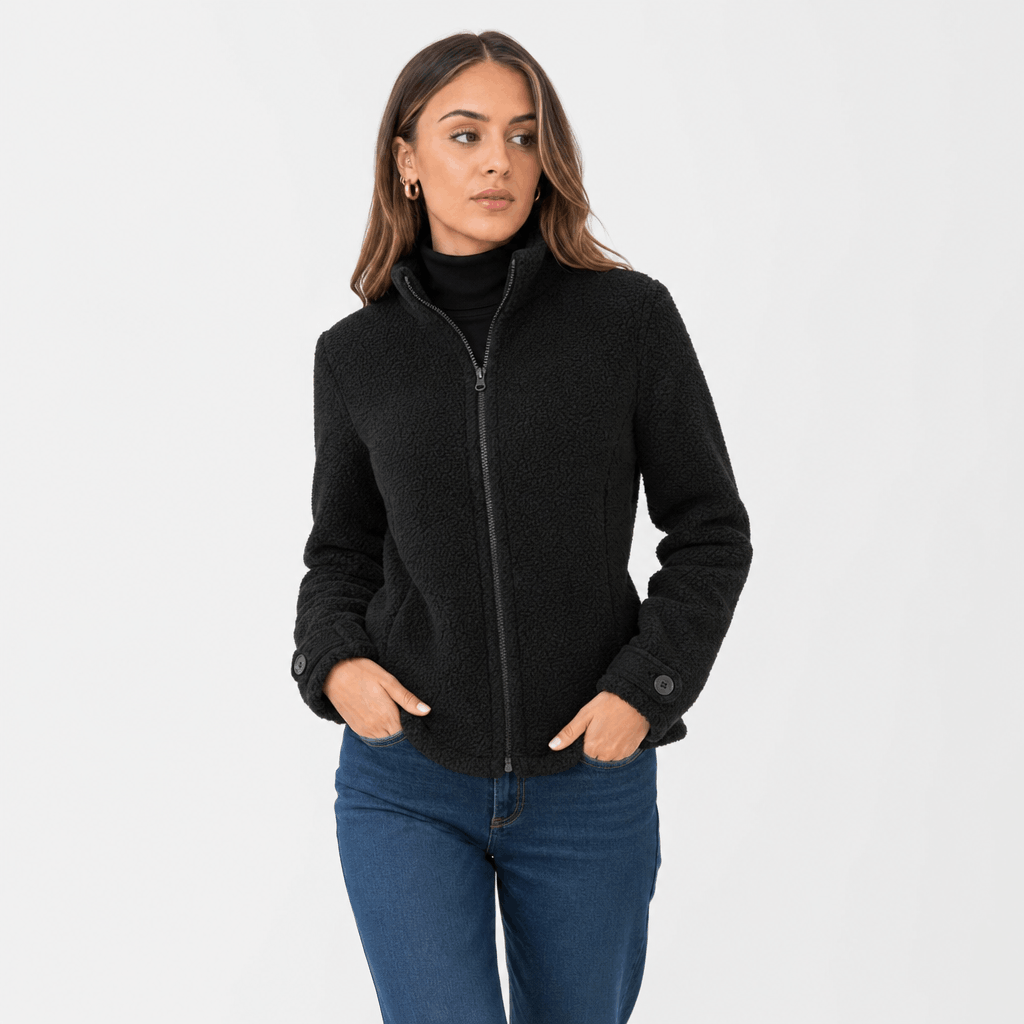 Female model wearing a black zip-up jacket with blue jeans.